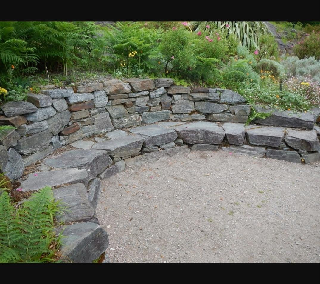 Dry stone curved seating wall in garden